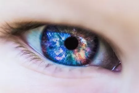 Up close image of child's eye with rainbow of colors reflected in it