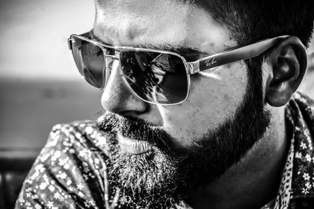 Black & white photo of a man in square aviator style Ray-Ban sunglasses