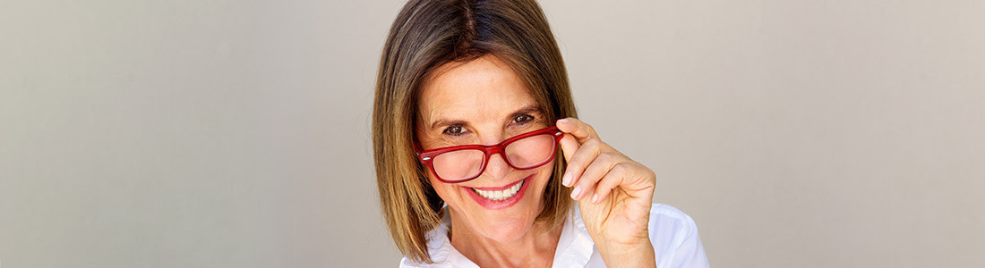 An older woman with red glasses smiling at the camera