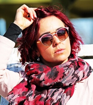Red haired woman wearing pink brow-line aviator style glasses