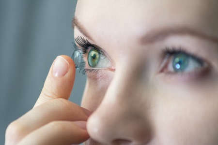 Woman with green eyes about to insert a soft contact lens